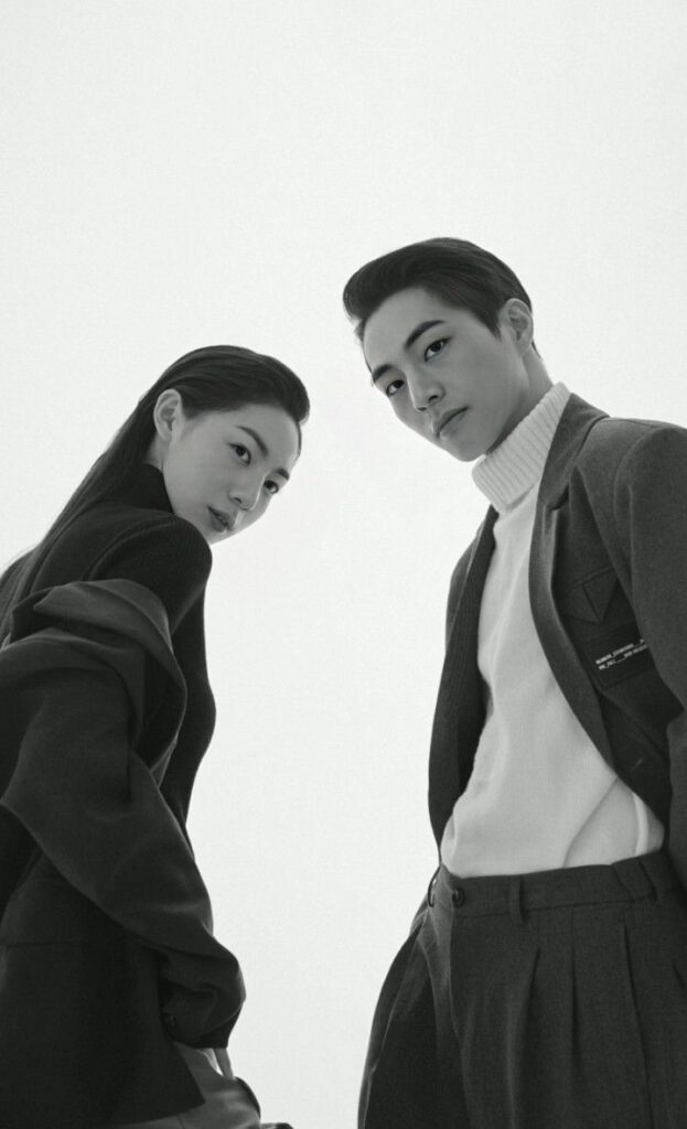 Fashionable duo in sleek outfits, gazing confidently in monochrome studio portrait.