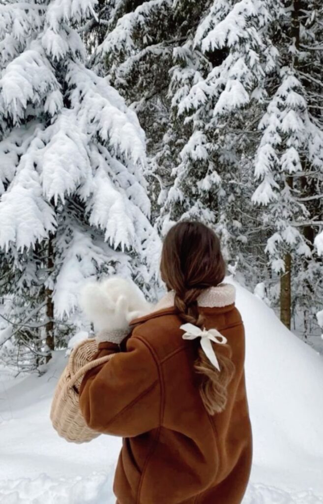 winter snow aesthetic Woman with braided hair and a winter coat in snowy forest, holding basket with white mittens. | Sky Rye Design Woman with braided hair and a winter coat in snowy forest, holding basket with white mittens.