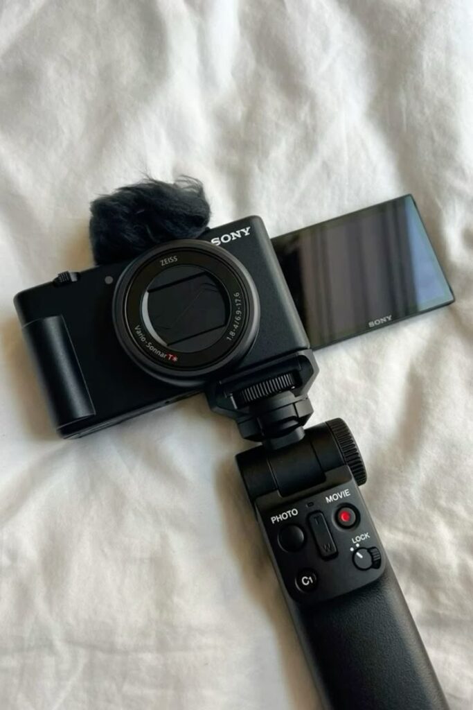 Sony camera with extended screen and grip on a white surface. Ideal for photography and vlogging.
