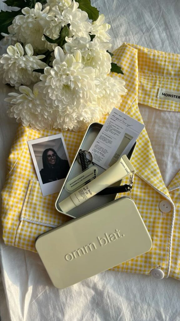 Визуал блеска для губ 💛 Yellow checkered shirt with skincare items and white flowers on a bed. | Sky Rye Design Yellow checkered shirt with skincare items and white flowers on a bed.