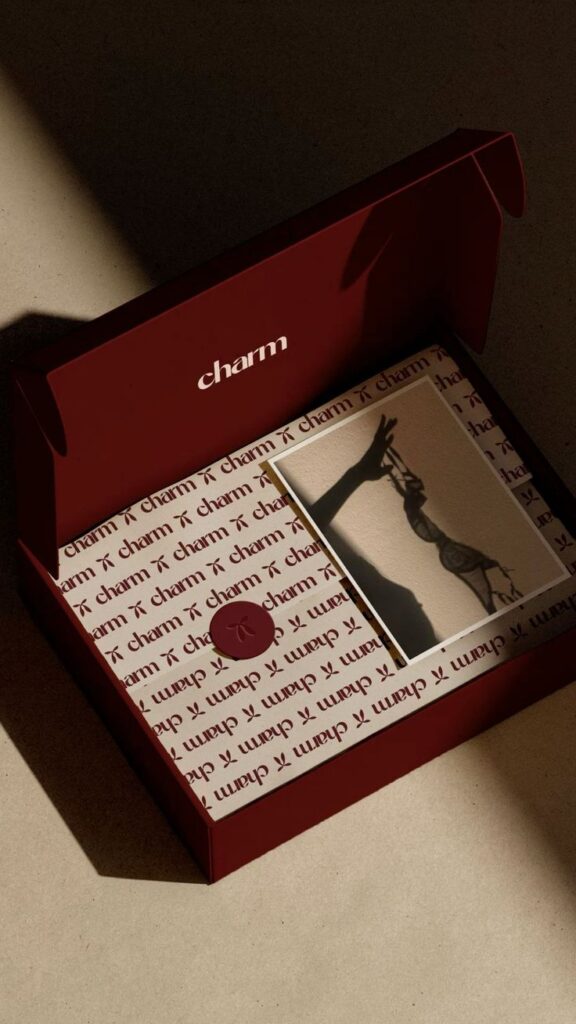 Elegant Charm package with a shadow of a hand and lace lingerie, set on stylish branded wrapping.