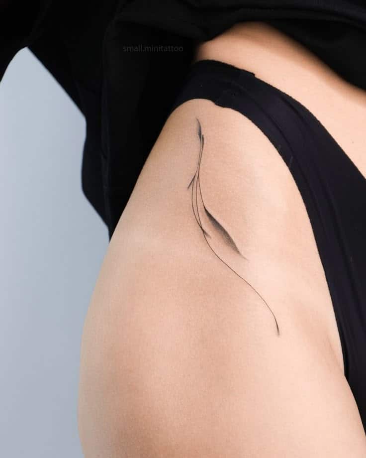Minimalist black ink tattoo on hip, abstract feather design in black underwear.