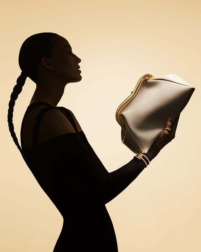 Silhouette of a woman in black dress holding a stylish white handbag, accentuating elegance and sophistication.