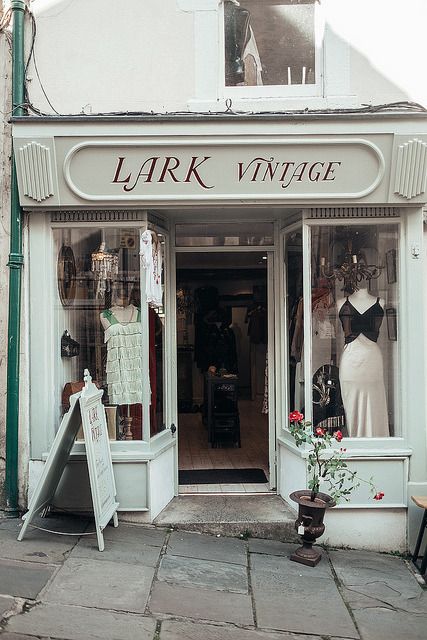 Lark Vintage shopfront with retro dresses and elegant window display on a quaint street.