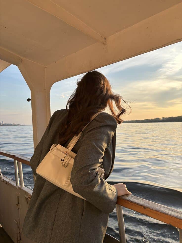 закат на Волге Woman with handbag gazing at sunset over water from boat deck. | Sky Rye Design Woman with handbag gazing at sunset over water from boat deck.