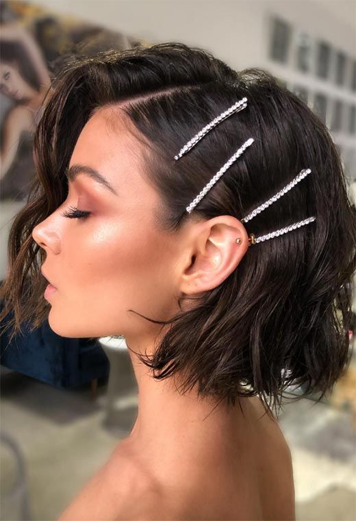 Short-haired woman with stylish bobby pins in side part, showcasing elegant hairstyles and ear piercings.