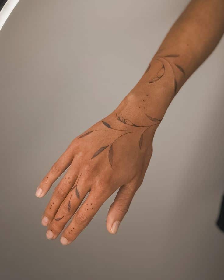 Hand adorned with delicate leaf tattoo design, minimalist body art on skin.