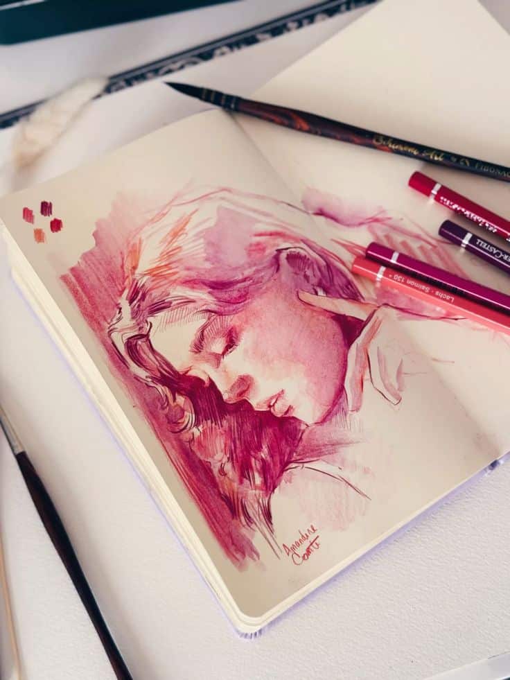 Sketchbook with a pink watercolor portrait and art supplies.