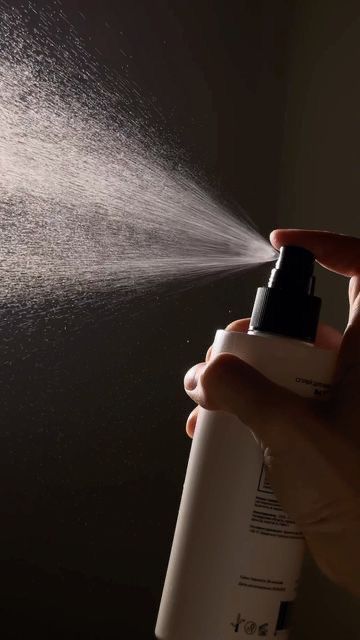 Л Hand holding spray bottle with misting nozzle, dark background, product in use. | Sky Rye Design Hand holding spray bottle with misting nozzle, dark background, product in use.