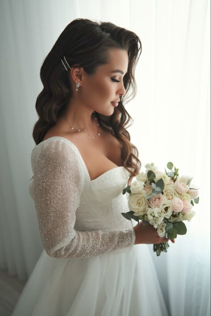 Свадебный букет Bride in sparkling white dress holding bouquet, standing by window with elegant hairstyle and jewelry. | Sky Rye Design Bride in sparkling white dress holding bouquet, standing by window with elegant hairstyle and jewelry.