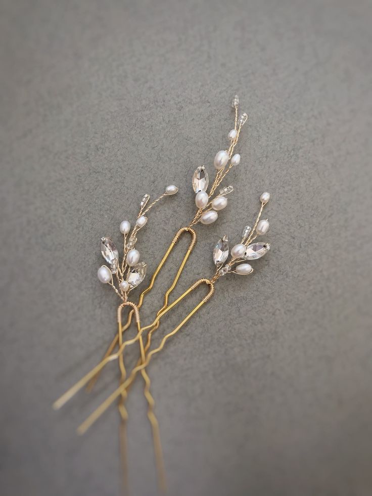 Elegant gold and pearl hairpins with crystal accents against a gray background, perfect for bridal or formal hairstyles.