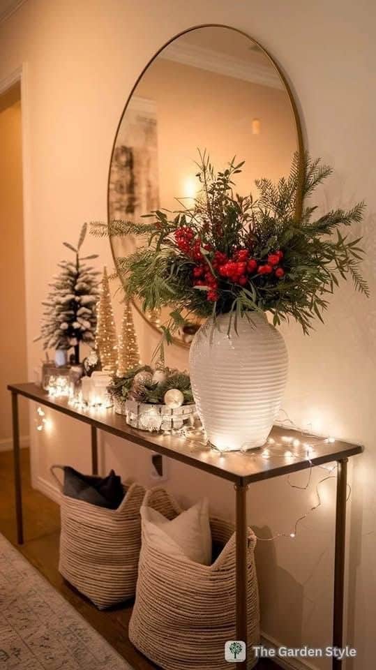 Elegant entryway with festive decor, including a large vase with red berries, gold trees, and decorative lights.