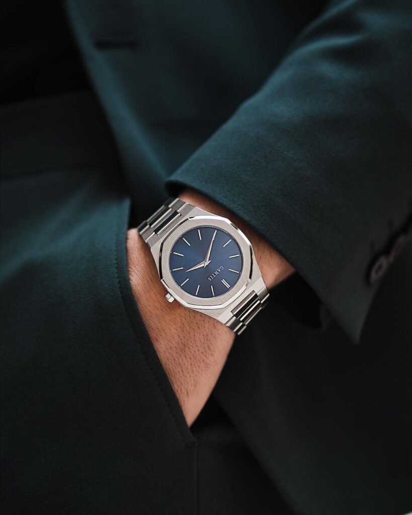 0de3de73f8280f3800f2a007ad86dcdf Stylish silver wristwatch with a blue dial worn with a dark green suit, showcasing elegant design and craftsmanship. | Sky Rye Design Stylish silver wristwatch with a blue dial worn with a dark green suit, showcasing elegant design and craftsmanship.