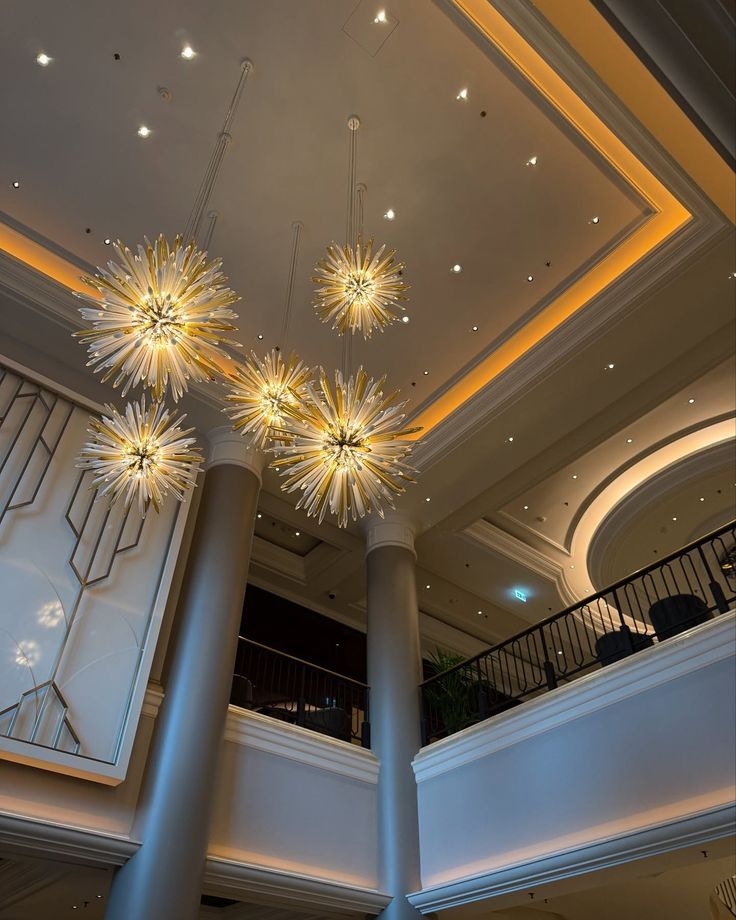 Modern chandelier lighting in a luxurious hotel lobby with high ceilings and elegant architectural details.