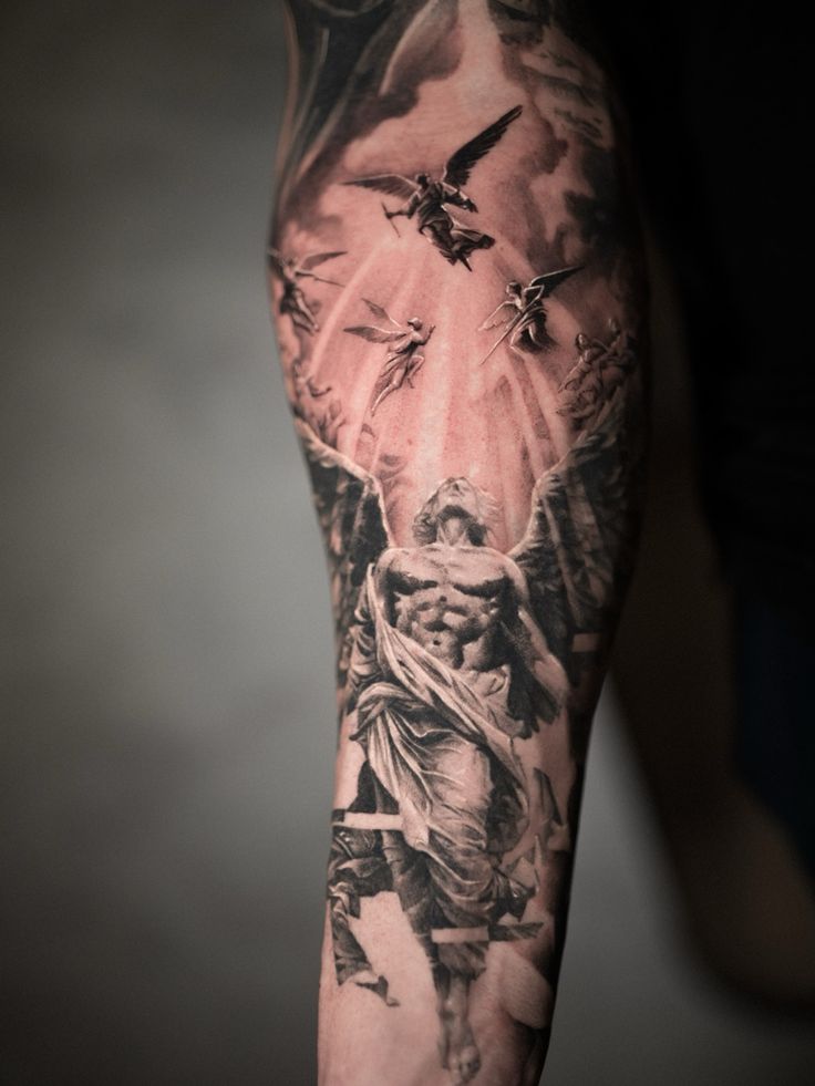 Intricate angel tattoo on forearm with detailed wings and clouds, showcasing a heavenly scene with multiple flying angels.