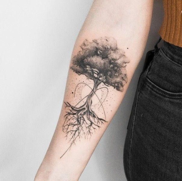 Arm tattoo featuring a detailed tree with roots, symbolizing growth and connection, in black ink.