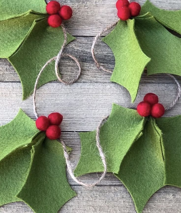 Felt Christmas garland with green holly leaves and red berries on a rustic wooden background.