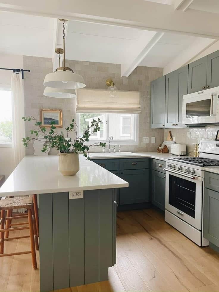 Bright modern kitchen with blue cabinets, wooden floors, white countertops, and plants on the island. Cozy and stylish.