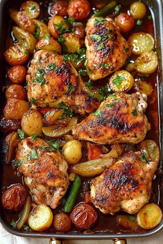 Roasted chicken thighs with potatoes and vegetables in a delicious glaze, garnished with fresh herbs.