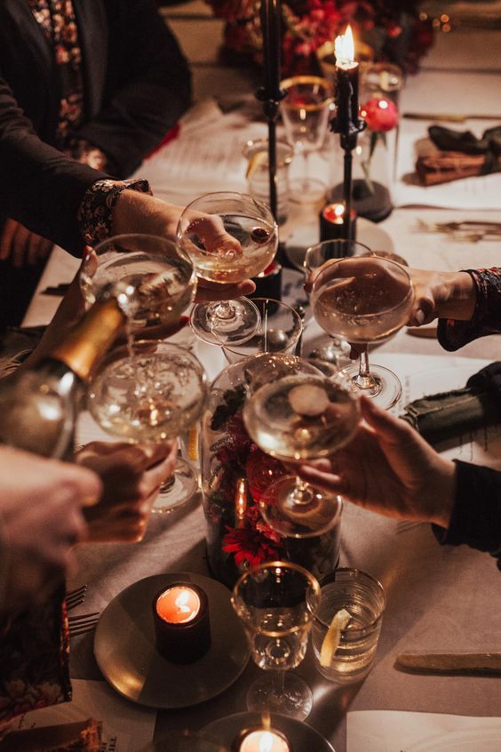 People toasting with champagne around a candlelit dinner table, creating a warm and festive atmosphere.
