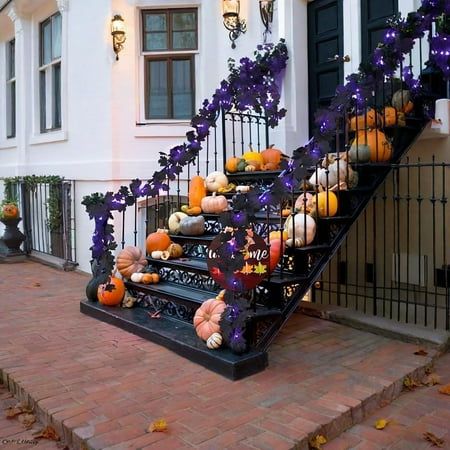 Festive Halloween staircase with pumpkins, purple lights, and autumn decor enhancing a cozy home entrance.
