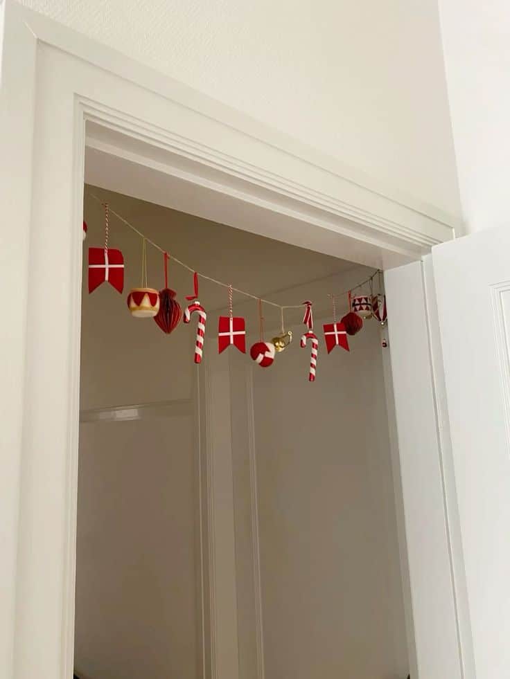 _ 10 Danish flag and candy cane garland hanging in a white doorframe, creating a festive holiday atmosphere. | Sky Rye Design Danish flag and candy cane garland hanging in a white doorframe, creating a festive holiday atmosphere.