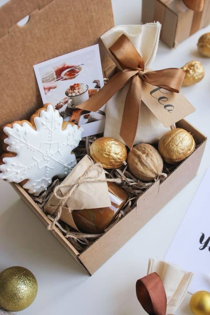 _ 10 Festive gift box with tea, snowflake cookie, and wrapped treats for a holiday celebration. | Sky Rye Design Festive gift box with tea, snowflake cookie, and wrapped treats for a holiday celebration.
