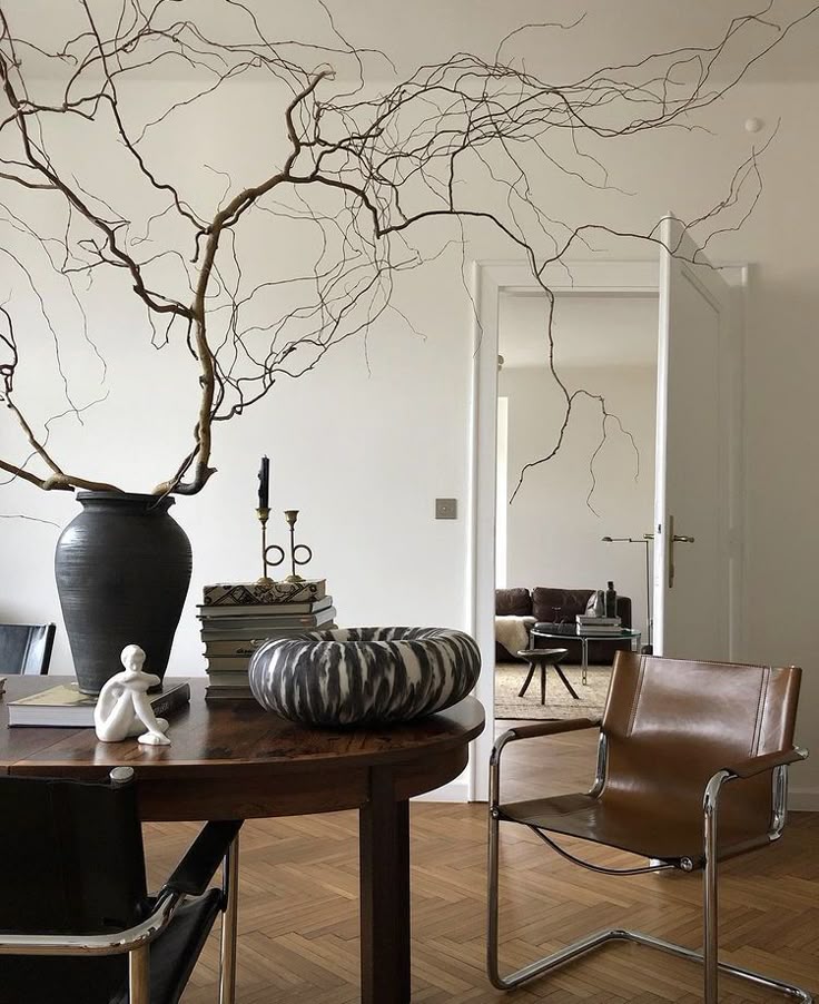 _ 10 Stylish modern living room with brown leather chair, dark vase, and artistic decor on wooden table. | Sky Rye Design Stylish modern living room with brown leather chair, dark vase, and artistic decor on wooden table.