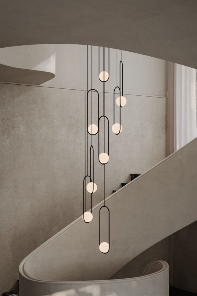 Modern pendant lights hanging over a spiral staircase in a minimalist interior design setting.