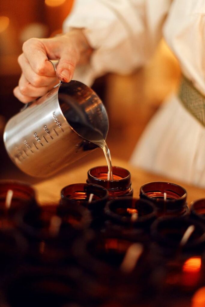 _ 11 Hand pouring wax into brown candle jars for handmade candle making. | Sky Rye Design Hand pouring wax into brown candle jars for handmade candle making.