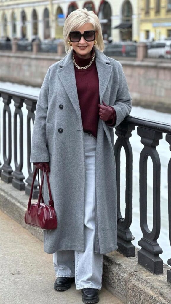 _ 11 Stylish woman in grey coat and sunglasses posing by canal, holding a red bag, urban background. | Sky Rye Design Stylish woman in grey coat and sunglasses posing by canal, holding a red bag, urban background.