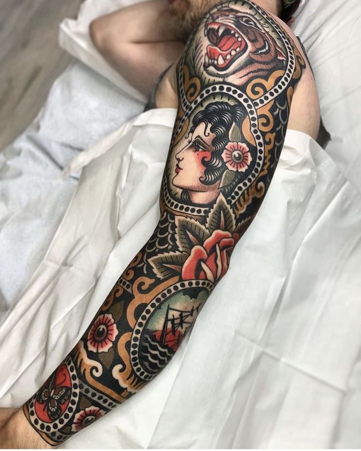 Colorful traditional sleeve tattoo with a tiger, woman's face, and floral designs on a person's arm.