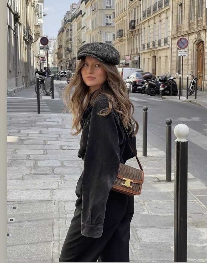 Woman in stylish outfit with cap and bag walking on a Parisian street.