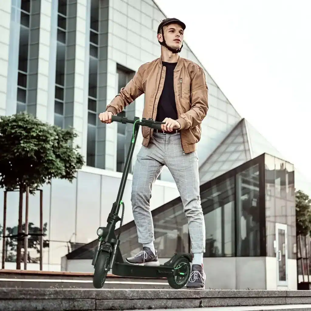 11_c48e20d0-e544-4bbc-9312-d36f0d388113_5000x Man on an electric scooter wearing a helmet, standing on steps in front of a modern building. | Sky Rye Design Man on an electric scooter wearing a helmet, standing on steps in front of a modern building.