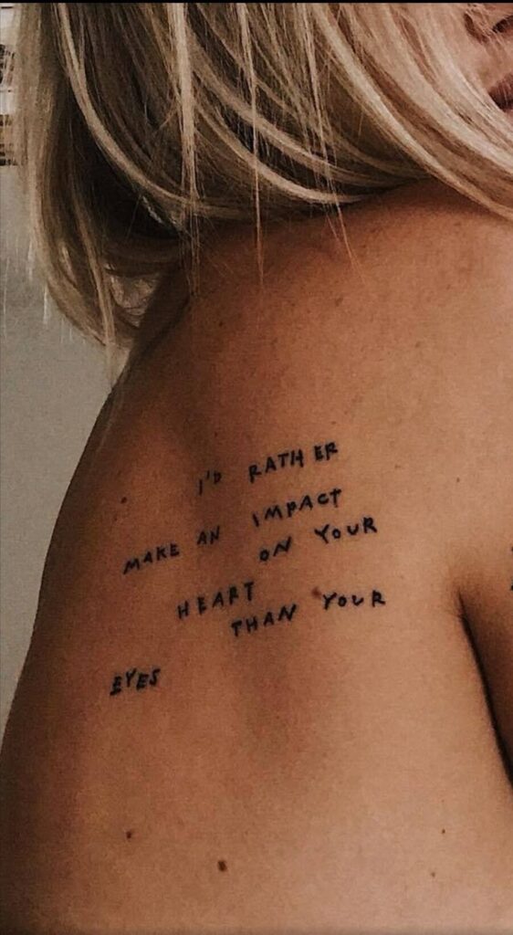_ 12 Close-up of a shoulder tattoo with the phrase I'd rather make an impact on your heart than your eyes. | Sky Rye Design Close-up of a shoulder tattoo with the phrase I'd rather make an impact on your heart than your eyes.