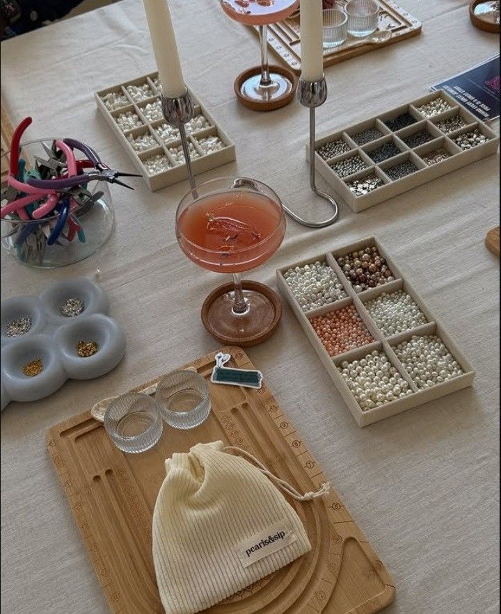 _ 12 Beading craft table with pearls, tools, candles, and a pink cocktail. Perfect setting for creative jewelry making. | Sky Rye Design Beading craft table with pearls, tools, candles, and a pink cocktail. Perfect setting for creative jewelry making.