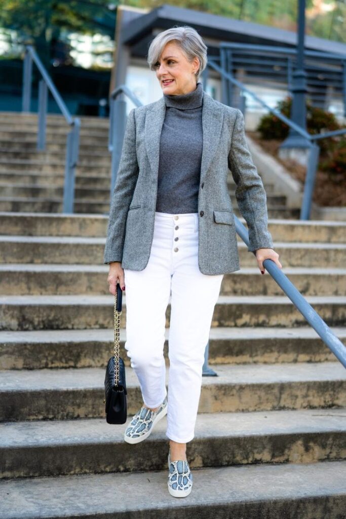 _ 12 Stylish woman in gray blazer and white pants walking down stairs, holding a black handbag. | Sky Rye Design Stylish woman in gray blazer and white pants walking down stairs, holding a black handbag.