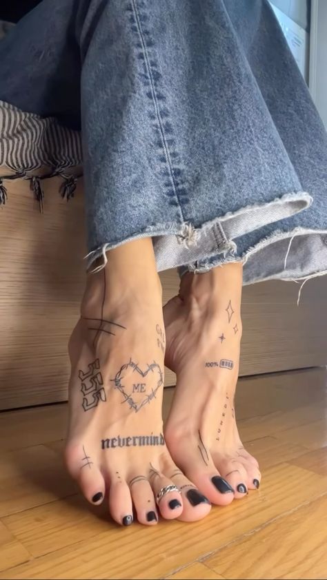 _ 12 Feet with artistic tattoos and black nail polish, wearing frayed jeans, on a wooden floor. | Sky Rye Design Feet with artistic tattoos and black nail polish, wearing frayed jeans, on a wooden floor.