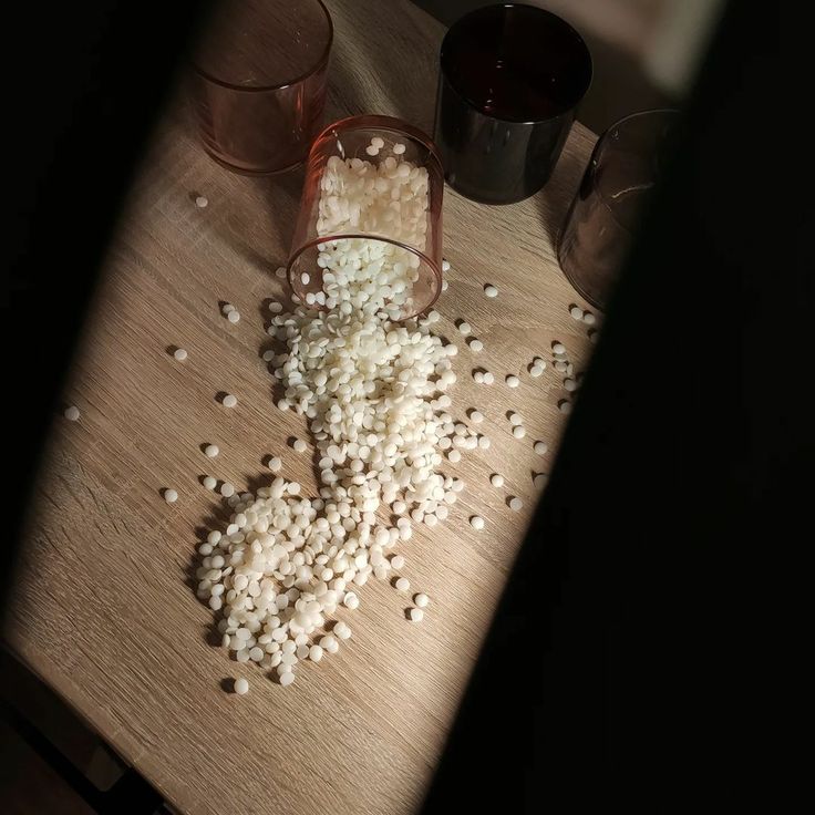 _ 13 Spilled white pellets from a tipped glass on wooden table, surrounded by other empty glasses in dim light. | Sky Rye Design Spilled white pellets from a tipped glass on wooden table, surrounded by other empty glasses in dim light.