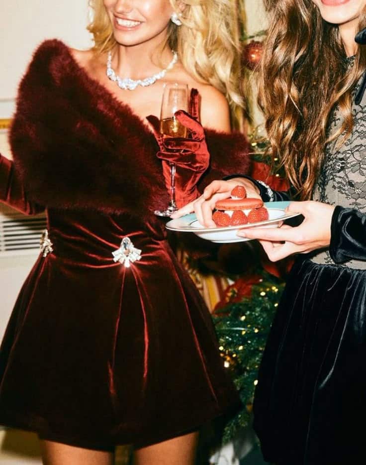 Two women in elegant dresses enjoying a festive party with champagne and strawberry desserts.