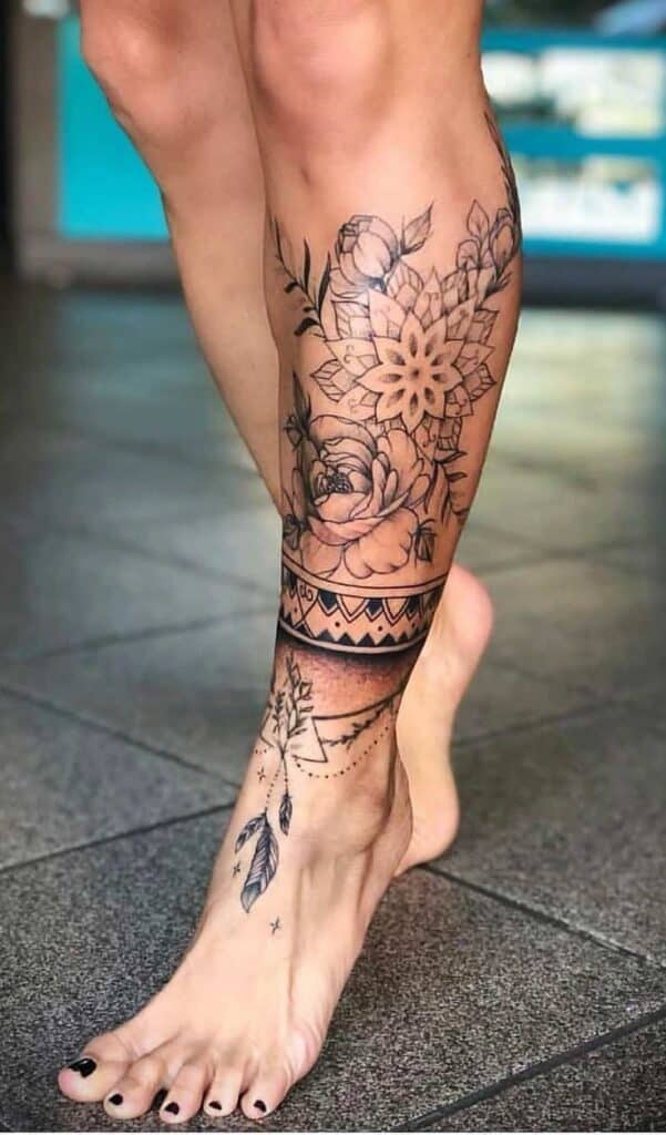 _ 14 Intricate leg tattoo featuring floral, geometric, and feather designs on a woman's calf and foot. | Sky Rye Design Intricate leg tattoo featuring floral, geometric, and feather designs on a woman's calf and foot.