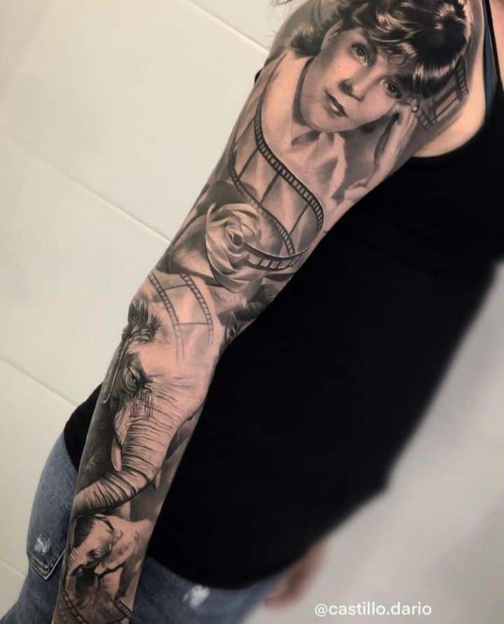 Intricate black and grey sleeve tattoo featuring a portrait, film strip, rose, and elephant design.