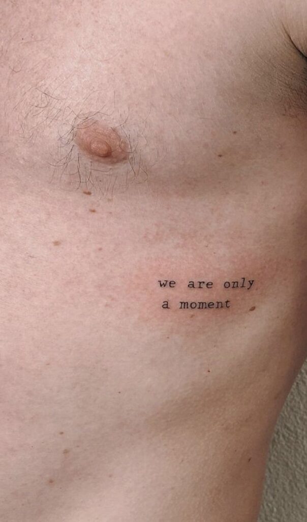 _ 15 Tattoo reading we are only a moment on a person's lower chest, minimalistic design. | Sky Rye Design Tattoo reading we are only a moment on a person's lower chest, minimalistic design.