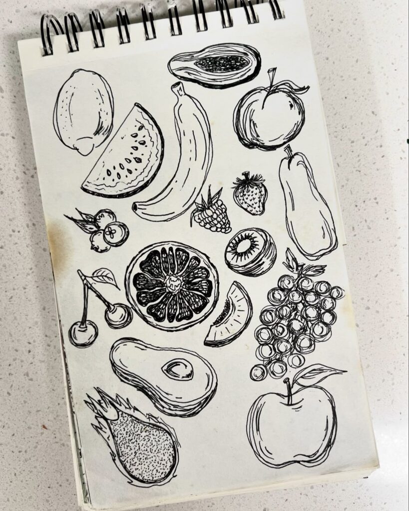 Sketchbook page filled with black ink drawings of various fruits, including banana, apple, and orange.