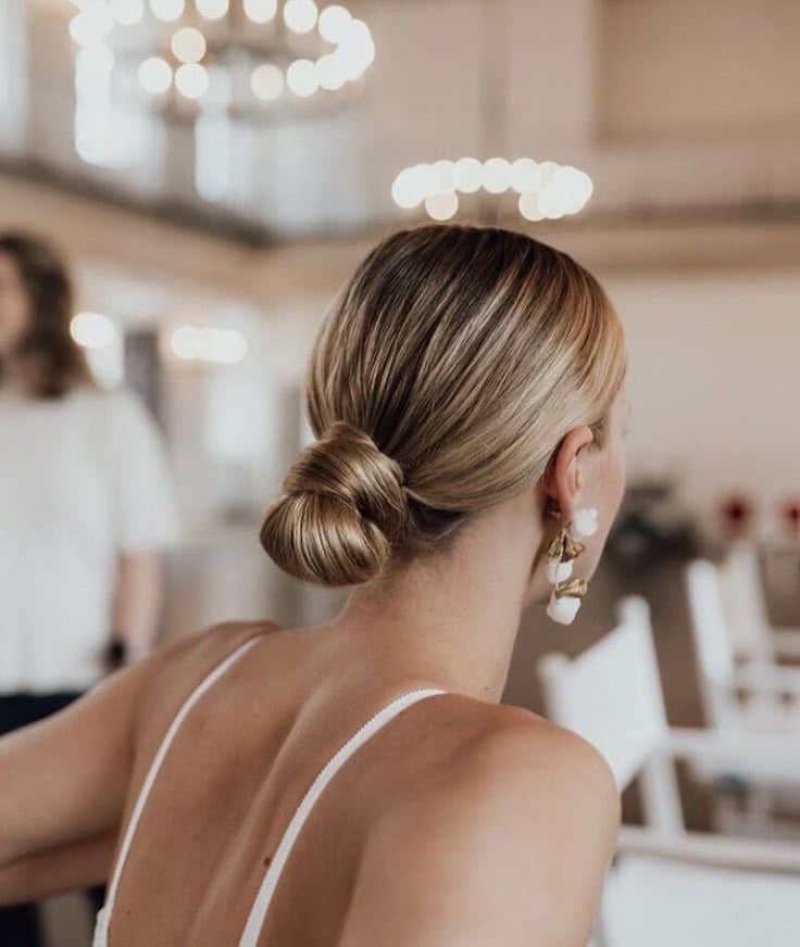 Elegant updo hairstyle with statement earrings in a chic indoor setting.