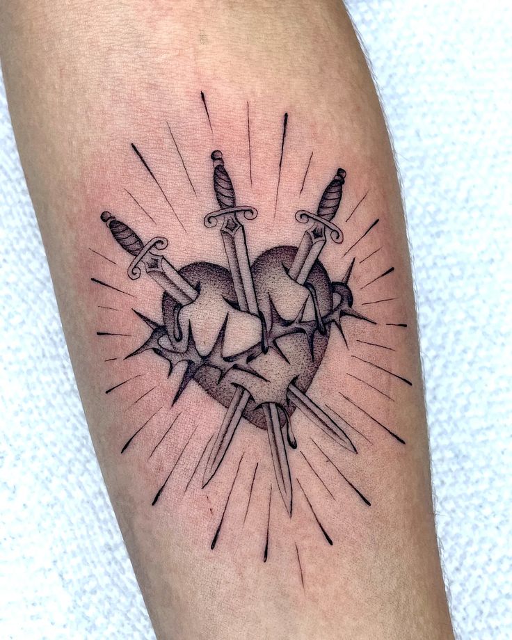 Heart tattoo with three swords and rays on skin, symbolizing strength and resilience. Black and gray ink design.