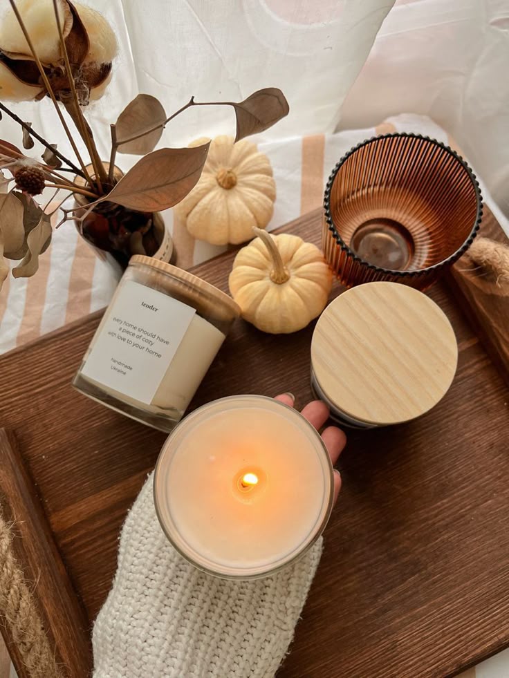 _ 17 Cozy autumn scene with lit candle, mini pumpkins, dried flowers, and sweater on wooden tray. | Sky Rye Design Cozy autumn scene with lit candle, mini pumpkins, dried flowers, and sweater on wooden tray.