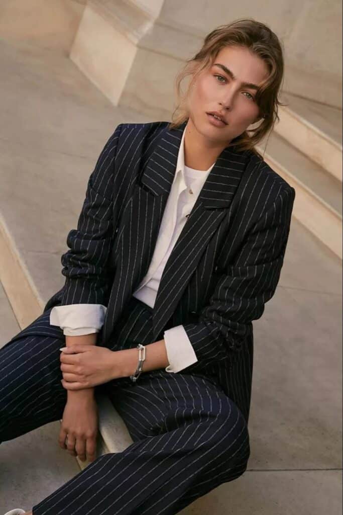 _ 17 Woman in pinstripe suit sitting on steps, exuding confidence and elegance. Fashionable business attire. | Sky Rye Design Woman in pinstripe suit sitting on steps, exuding confidence and elegance. Fashionable business attire.