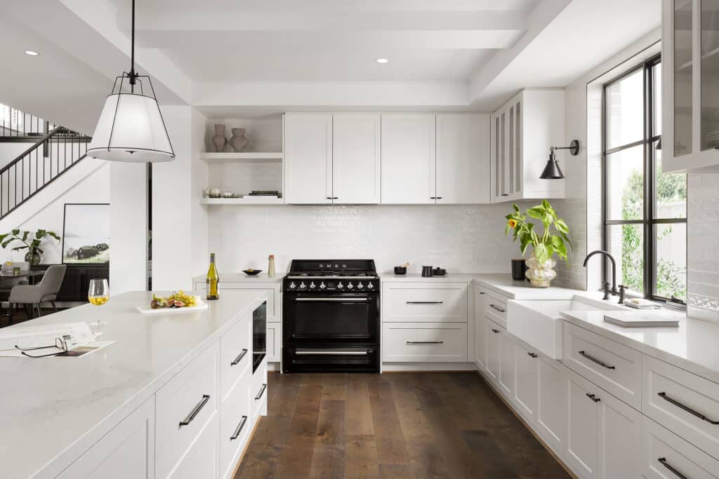 1726456967_original Modern kitchen with white cabinets, large island, black stove, and wooden flooring, enhanced by natural light. | Sky Rye Design Modern kitchen with white cabinets, large island, black stove, and wooden flooring, enhanced by natural light.