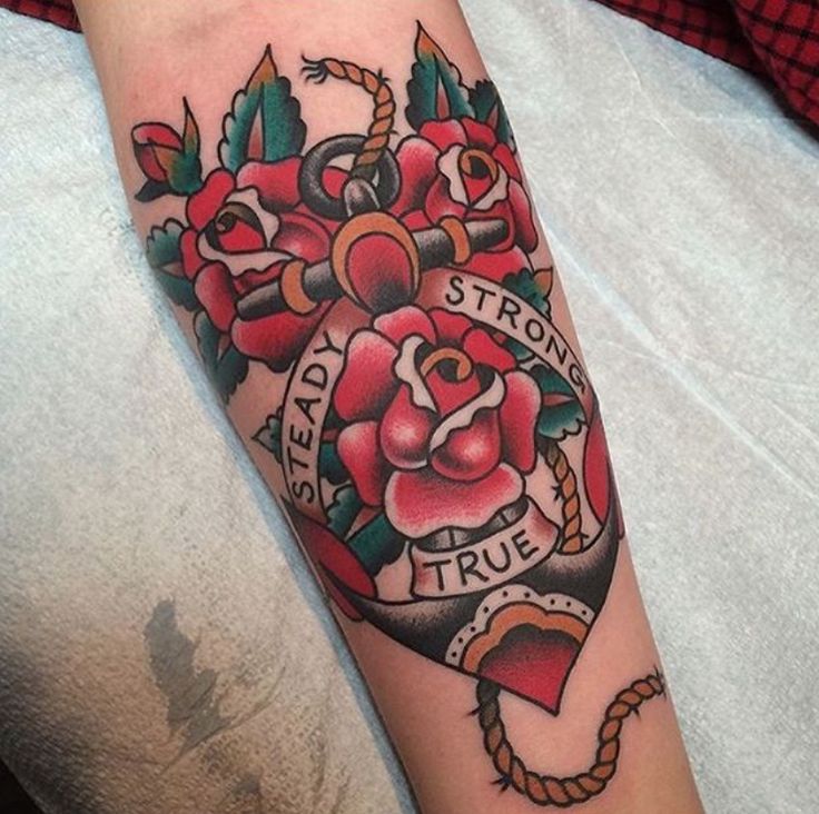 Colorful tattoo of roses on an arm with the words Steady, Strong, True intertwined with an anchor design.